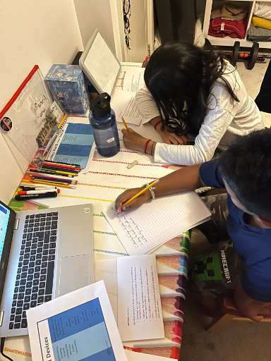 two children sitting at a desk having online tutoring from Helen on the laptop in front of them